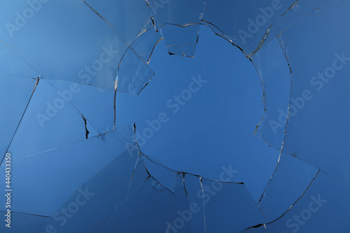 Closeup view of broken glass with cracks on blue background photo