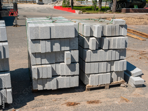 Noyabrsk, Russia - June 5, 2021: Sidewalk slab standing on a wooden pallet on the asphalt. The large gray paving slab is stacked in rows and ready to be laid.