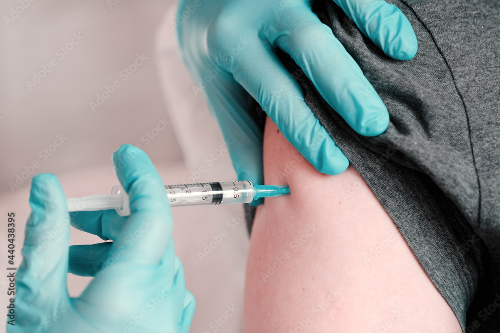 The doctor who gives the patient a vaccine, a vaccination against coronavirus infection. Medical concept of subcutaneous injection vaccination. The doctor who gives the patient a vaccine, a vaccination against coronavirus infection. Medical concept of subcutaneous injection vaccination.