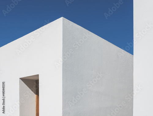 Clean minimalist Mediterranean style building against a clear blue sky.