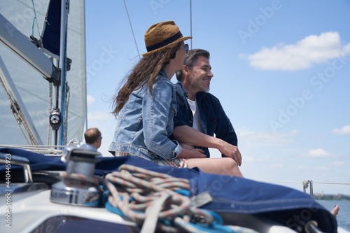 Happy smiling couple sitting on sailing boat enjoying summer and vacation travel.
