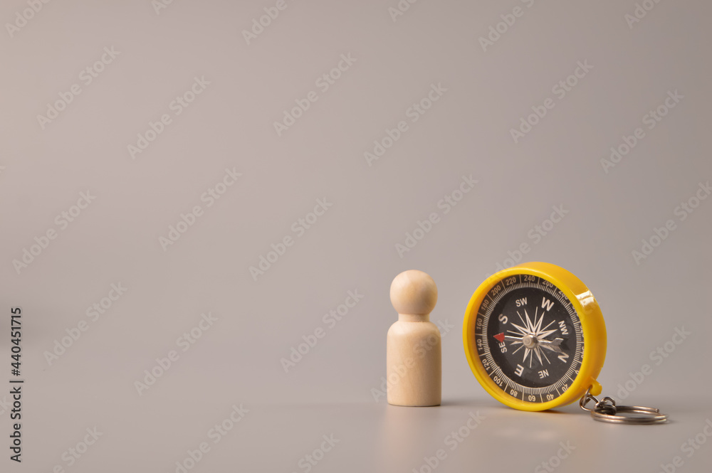 Wooden doll figure and magnetic compass. Symbol of strategy and future vision Wooden doll figure and magnetic compass. Symbol of strategy and future vision