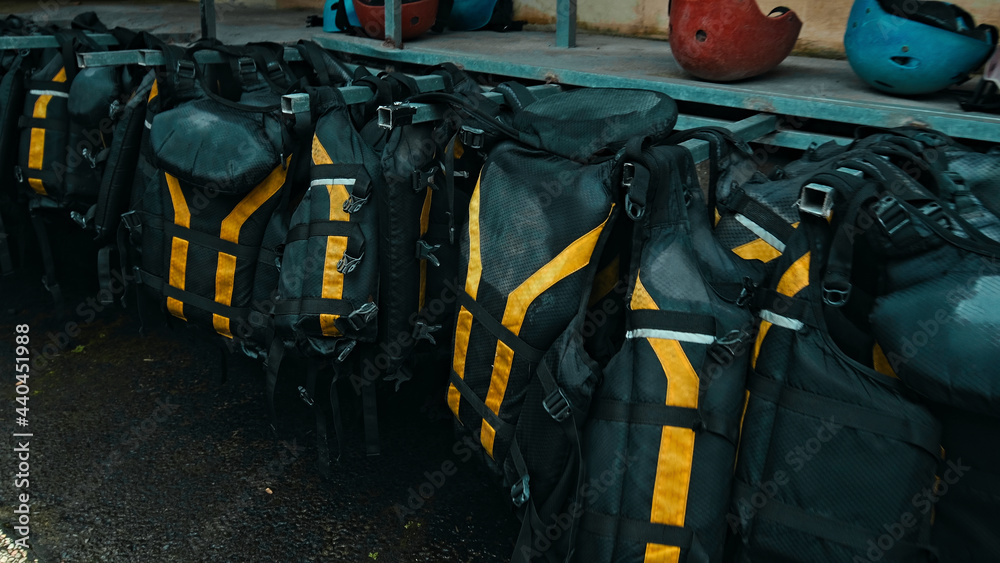.Black protective jackets with yellow lines to practice rafting hanging on a wall