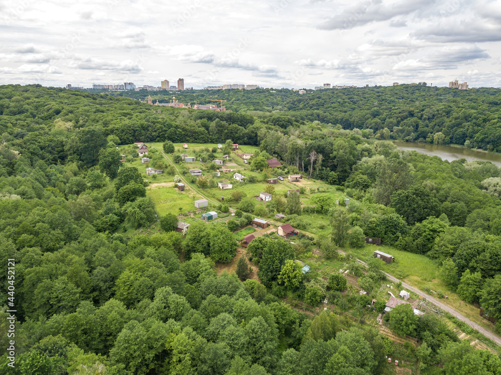 Low-rise settlement among green deciduous forest. Aerial drone view. Low-rise settlement among green deciduous forest. Aerial drone view.