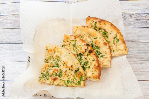 Portions of traditional hindu naan garlic bread on absorbent paper and lots of parsley photo
