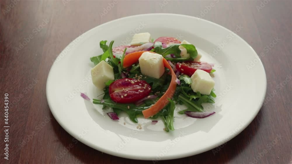 someone eat fresh salad with cheese arugula cherry tomatoes red onion sesame seeds close up