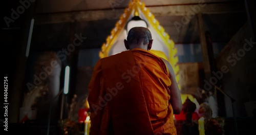 A back view slow motion of Buddhist monk kneels and pays homage to the Buddha three times in a very old church. photo