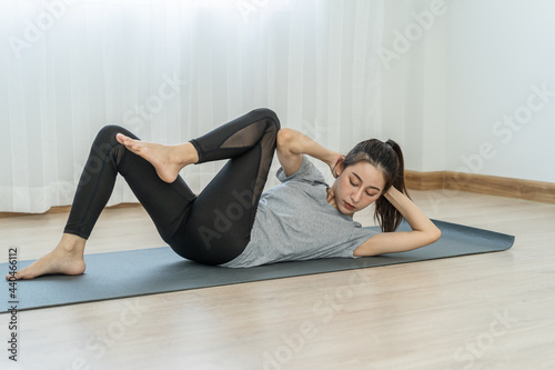 Fit, sporty asian young beautiful woman, girl lying physical or pilates, exercise training on mat or asana for wellbeing, healthy care at home. Workout fitness exercise person in casual wear at home.