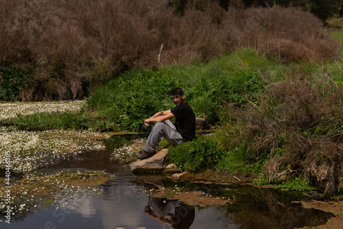 person sitting on a rock in the river at spring