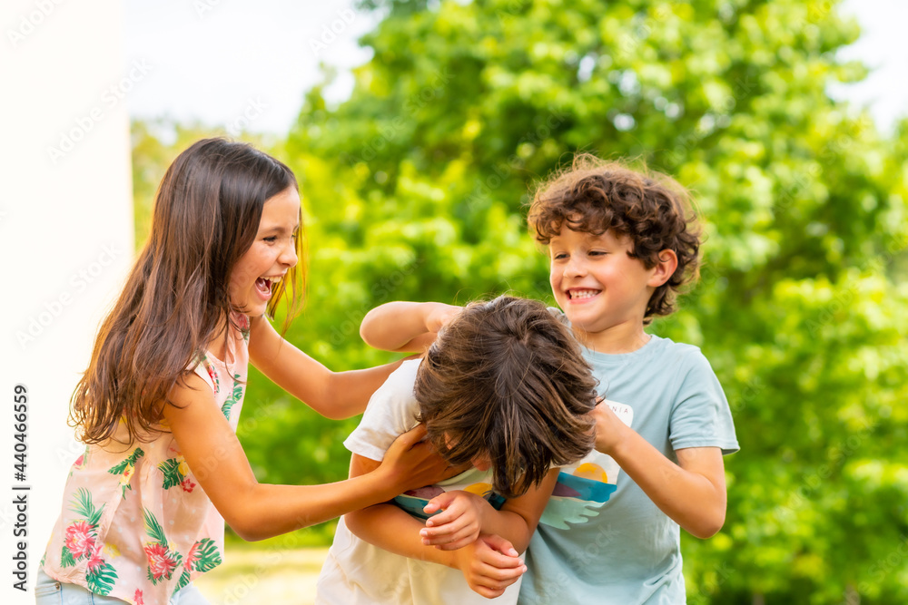 Lifestyle of three brothers smiling and playing together in a park, friends and brothers enjoying as a family, tickling each other Lifestyle of three brothers smiling and playing together in a park, friends and brothers enjoying as a family, tickling each other