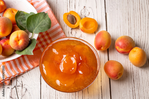 Apricot fruits and apricot jam on the wooden background