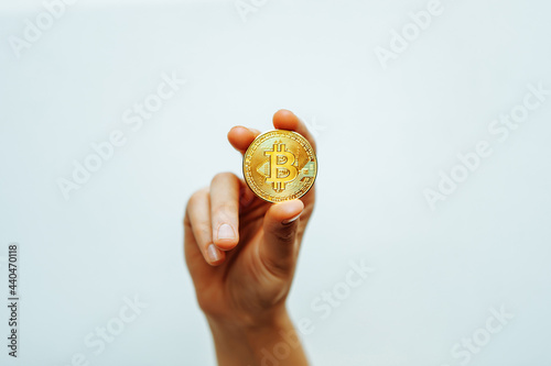 Bitcoin in hand on a light background.