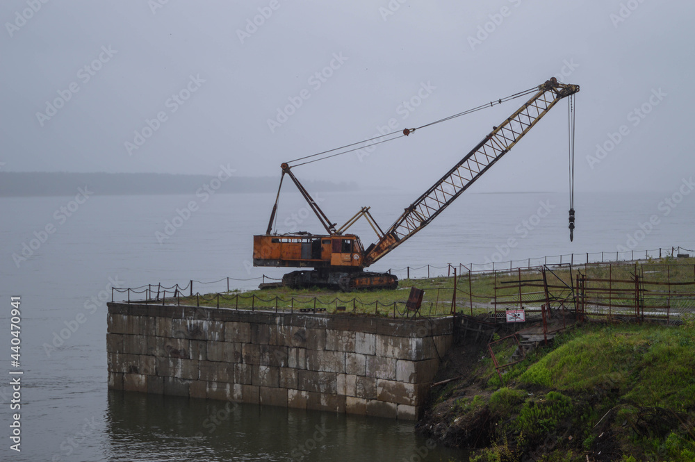Old rusty abandoned orange crane on the river Old rusty abandoned orange crane on the river