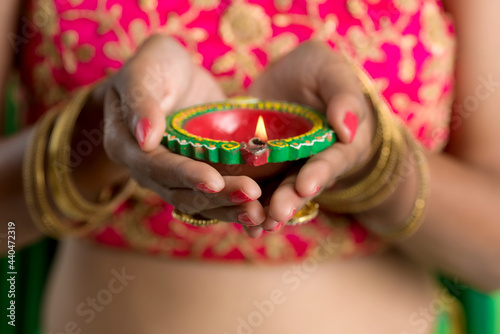 Portrait of a Indian Traditional Girl holding Diya, Girl Celebrating Diwali or Deepavali with holding oil lamp during festival of light on white background