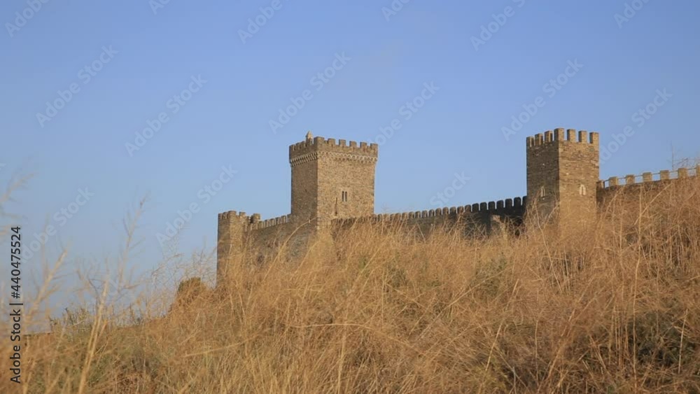 Bottom view of ancient Genoese fortress in Sudak town. Historic architectural landmark at sunset. Crimea. Bottom view of ancient Genoese fortress in Sudak town. Historic architectural landmark at sunset. Crimea.