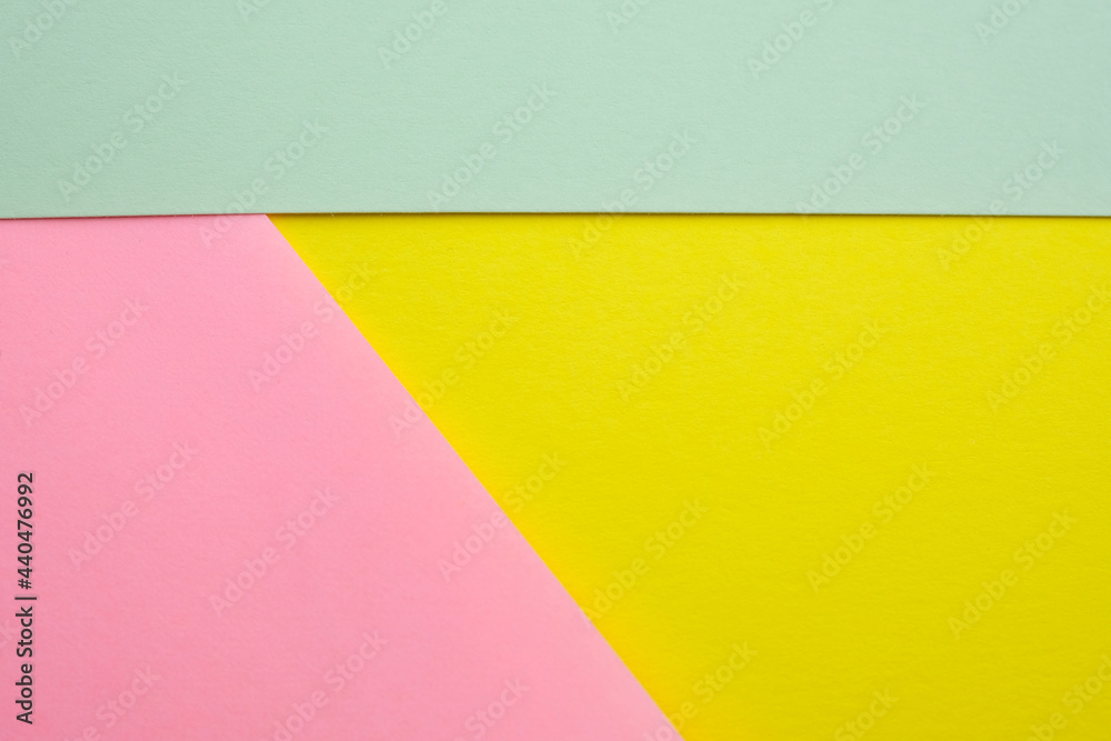 Abstract colored background made with three pieces of cardboard top view. Segmented background of green, yellow and pink. Different colors paper background.