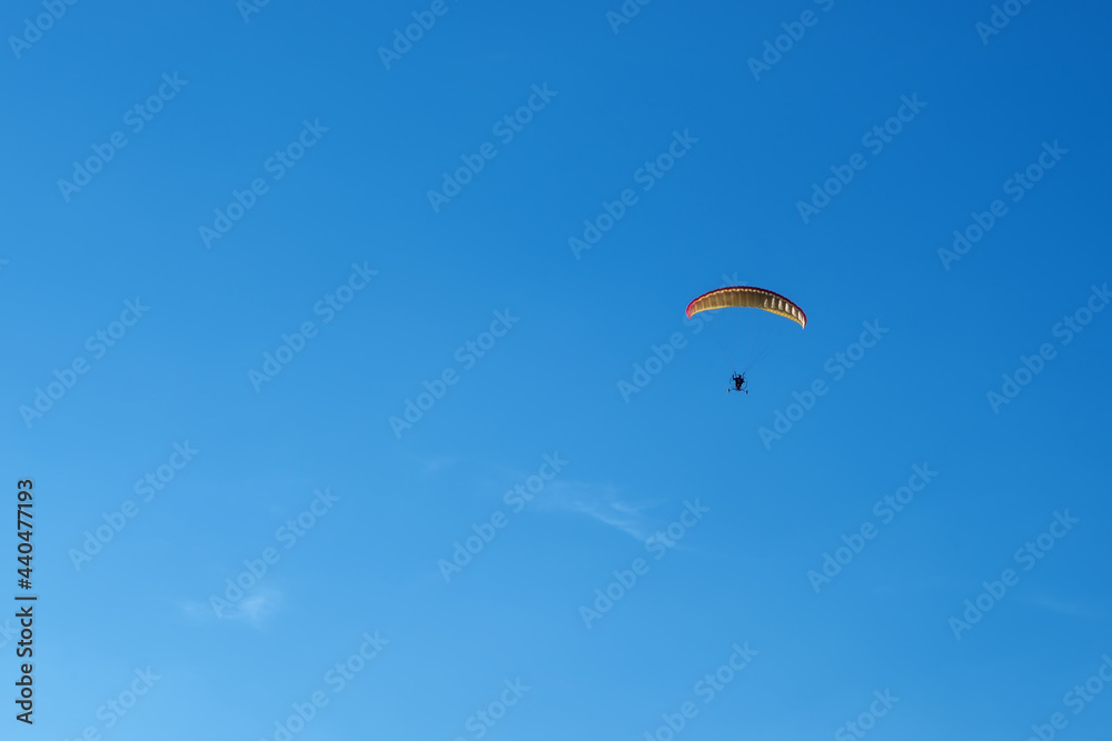 Hang glider with motor in the blue sky on landing Hang glider with motor in the blue sky on landing