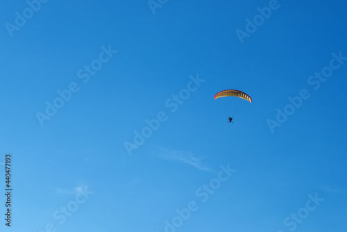 Hang glider with motor in the blue sky on landing
