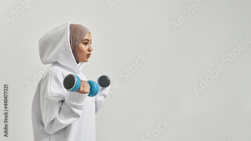 Photography Attractive young arabian woman in hijab holding dumbbells