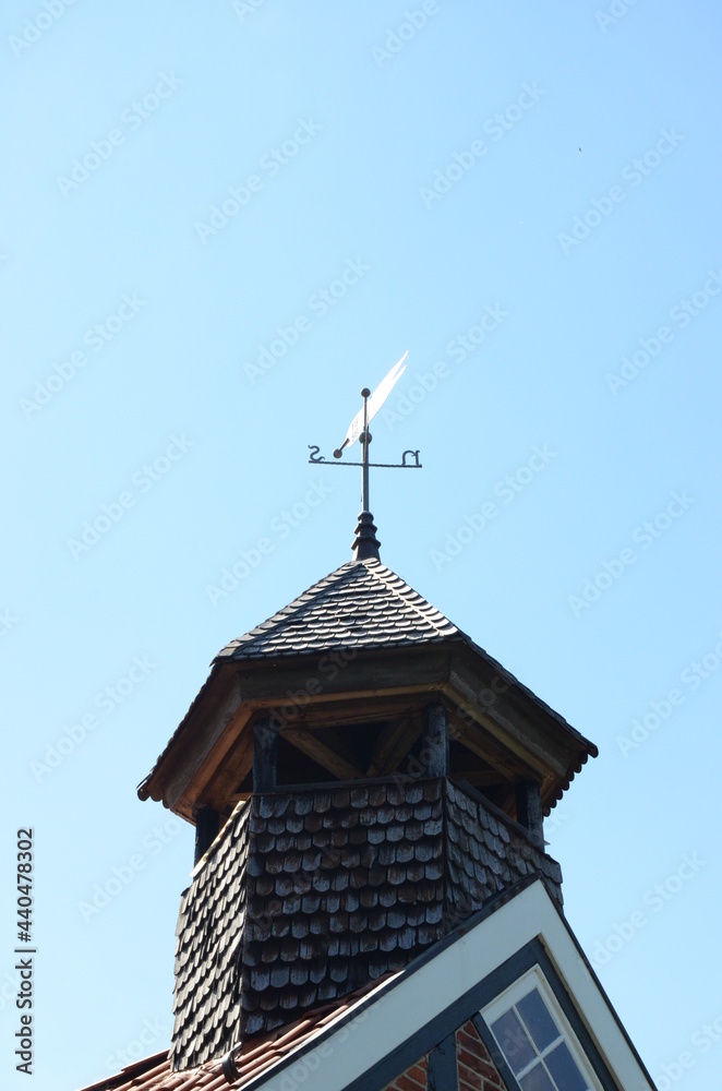 weather vane on the roof top of a tower under sun light