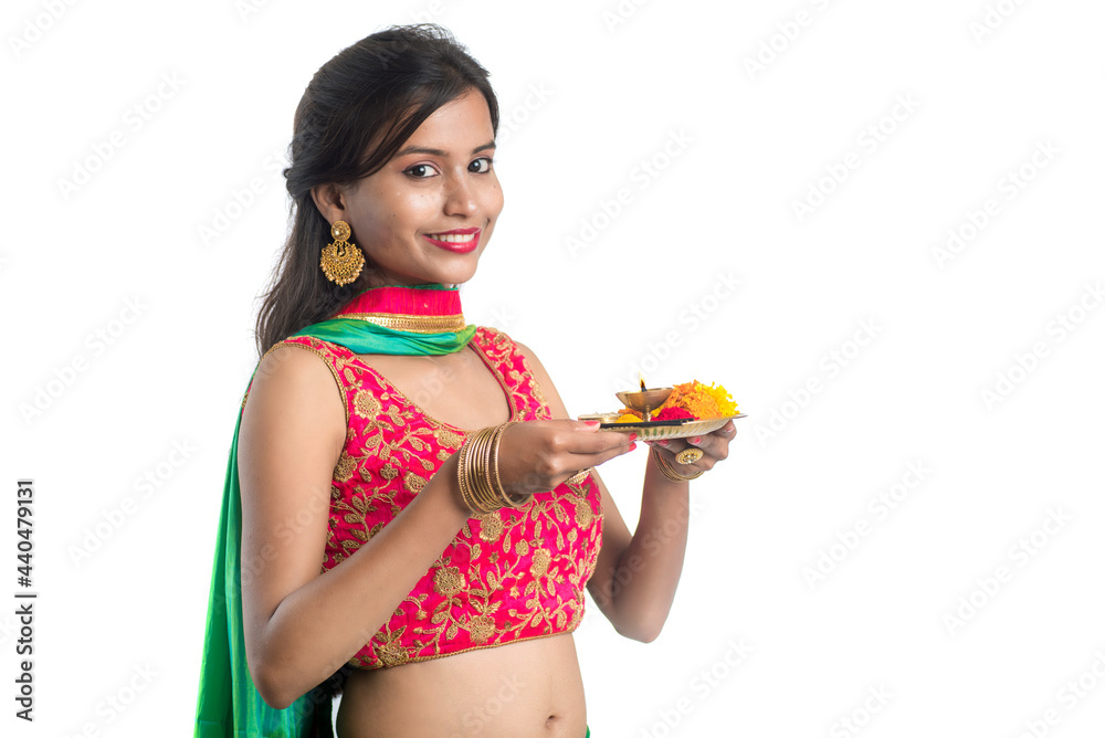 Beautiful Indian young girl holding pooja thali or performing worship on a white background Beautiful Indian young girl holding pooja thali or performing worship on a white background