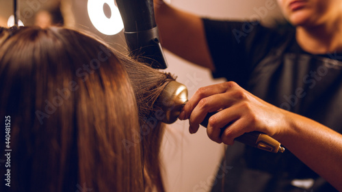 coloring hair, Hair dyeing. Young professional hairdresser applies hair dye to a female client photo
