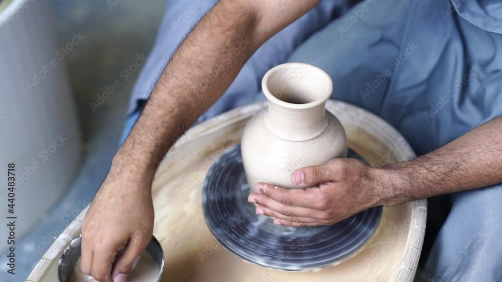 Above. Male hands sculpt a clay vase on a potter's wheel by adding clay. Interesting hobby Above. Male hands sculpt a clay vase on a potter's wheel by adding clay. Interesting hobby