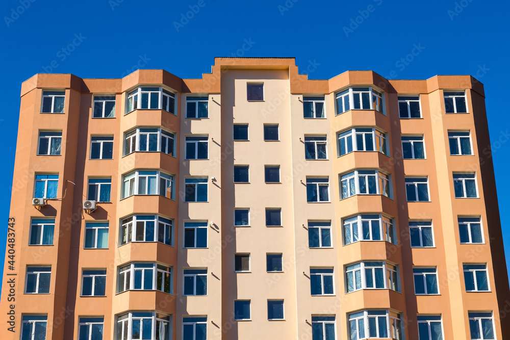 New multi-storey, apartment building, against a blue sky, bottom view.