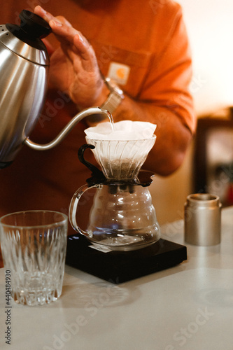 Barista pouring water over the coffee powder on dripper cup