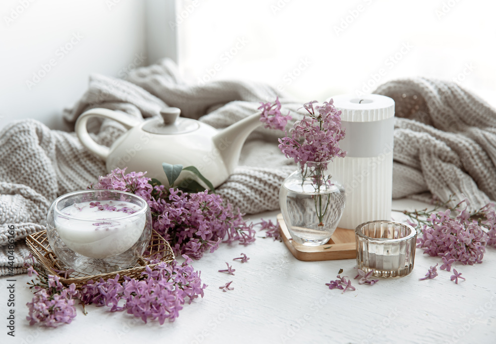 Spring home still life with a cup of milk and lilac flowers.