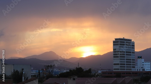 Paisaje de un día lluvioso de un polígono industrial con el fondo de una montaña y una torre de edificios.