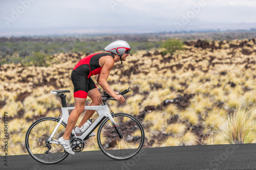Cycling sport athlete man biking on triathlon bike. Fit male cyclist on professional triathlon bicycle wearing time trial helmet for iron man race exercising in Kailua Kona, Big Island, Hawaii, USA. © Maridav