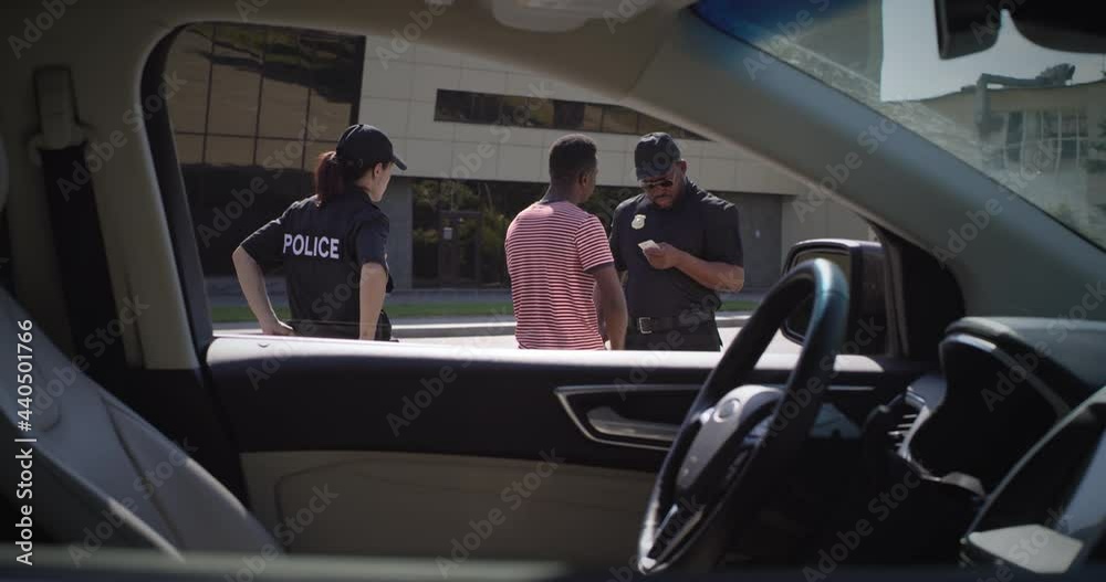 Diverse police officers checking documents of black driver Diverse police officers checking documents of black driver