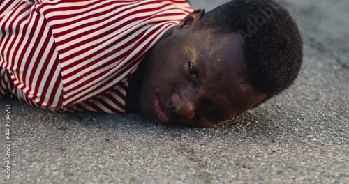 Upset black guy lying on ground during arrest photo