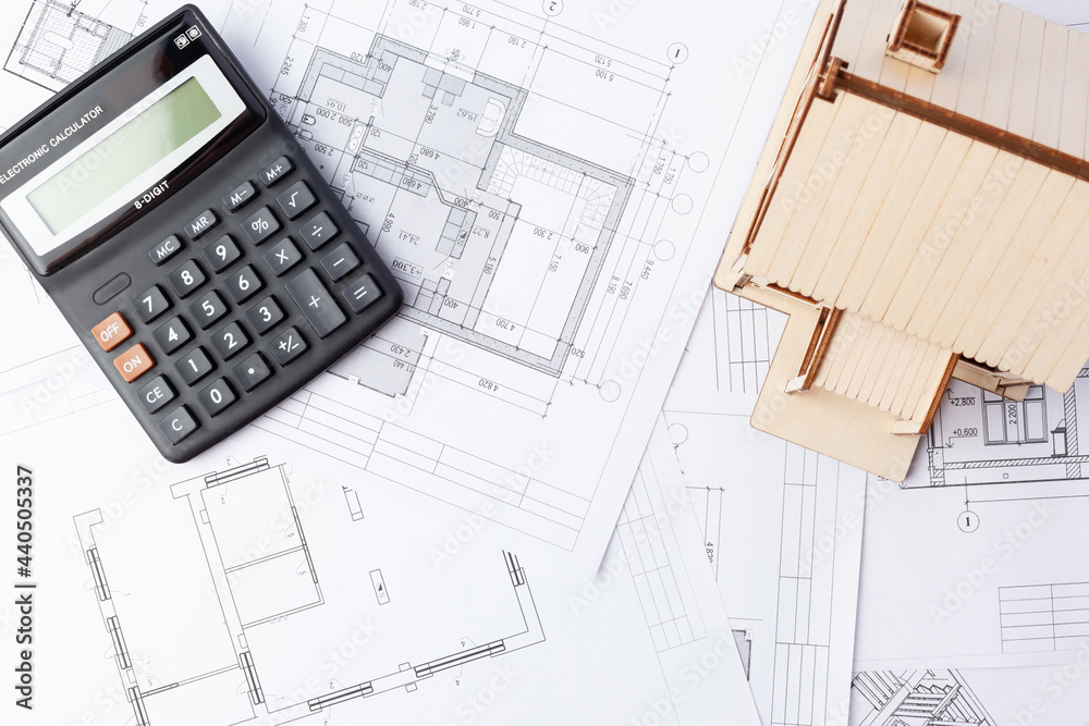 calculator and wooden house against the background of drawings calculator and wooden house against the background of drawings
