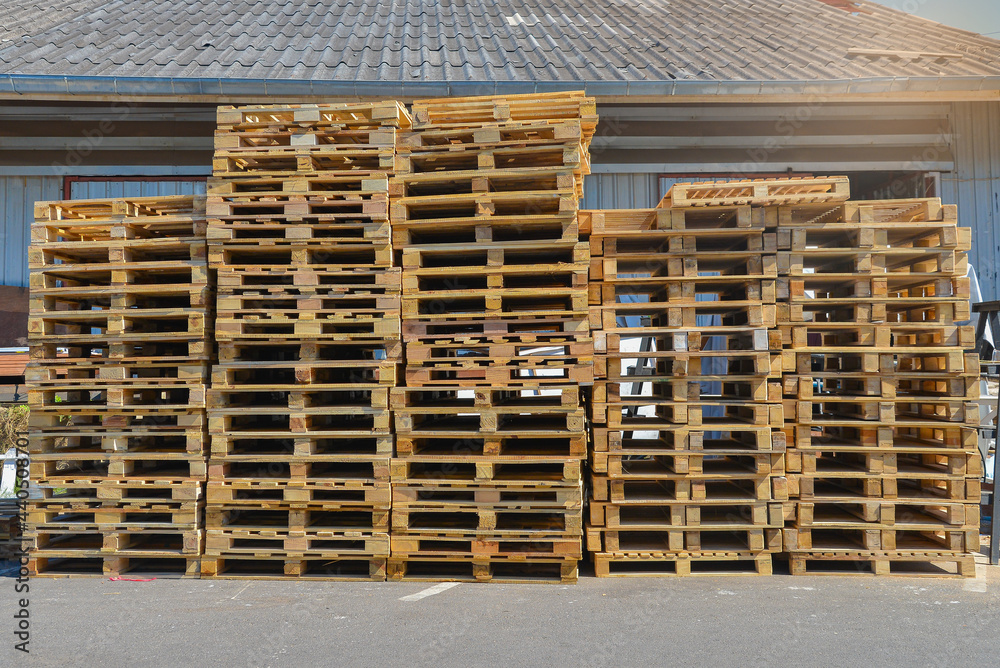 A stack of pallets sit outside a building, Wooden pallet. A stack of pallets sit outside a building, Wooden pallet.