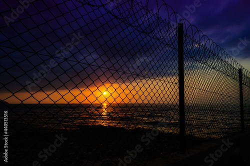 wire fence in calm sunset and ocean view 
