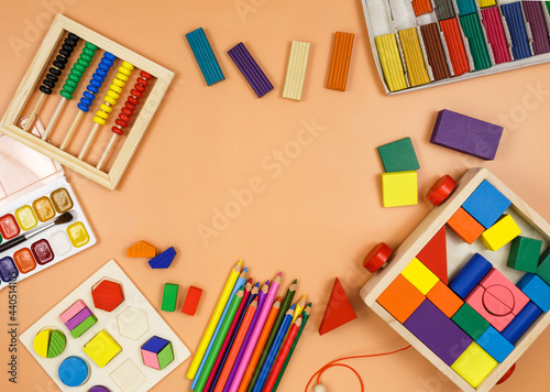 Colorful cubes, paints, pencils, blocks, modeling clay on orange background. Interesting math, games for preschool for kids. Education, back to school concept