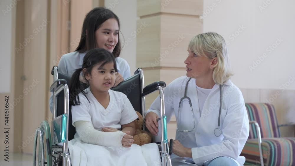 Female pediatrician doctor and child patient on a wheelchair with her mother in the health medical center
