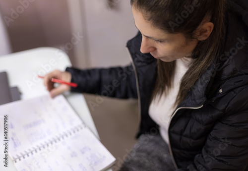 Mulher trabalhando em casa, usando lápis, caderno e celular. Fazendo anotações se comunicando com clientes através de seu smartphone. Plano de fundo desfocado.