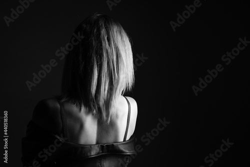 Portrait of a woman in a leather jacket and lingerie, black and white photo. Beautiful caucasian woman of nationality sensitive portrait on black background