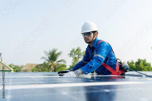 A worker wearing fall protection safety equipment while installing the solar panels at roof top of building. Concept of economic energy. High safety standard working procedure.