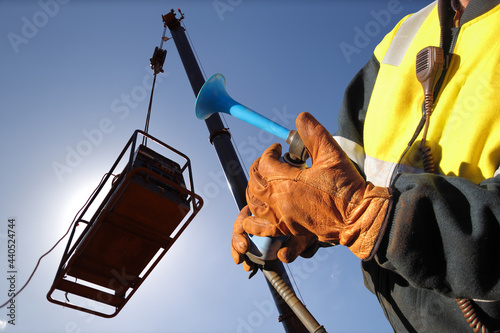 Foto Trained competent rigger hand wearing a safety leather glove using air horn sign