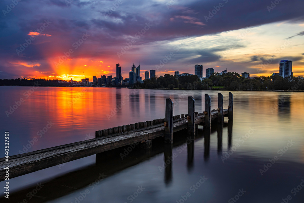 Sunset with Sunrays at Swan River, with jetty in foreground, and Perth City in background