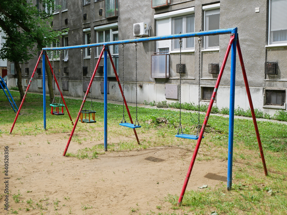 Swings at the playground next to an apartment building Swings at the playground next to an apartment building