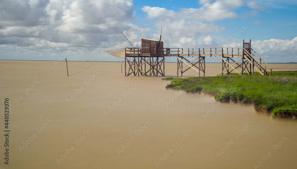 Calm brackish water of Gironde estuary, France with fishing hut on coastline of Charente-Maritime