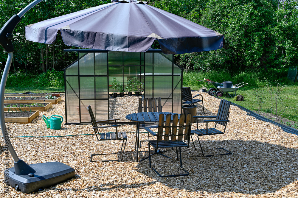Obraz premium greenhouse table and chairs with sunshade in garden