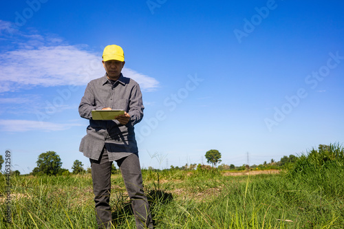 Smart farmer uses a tablet to monitor and analyze the crops in his farm during a sunny day.