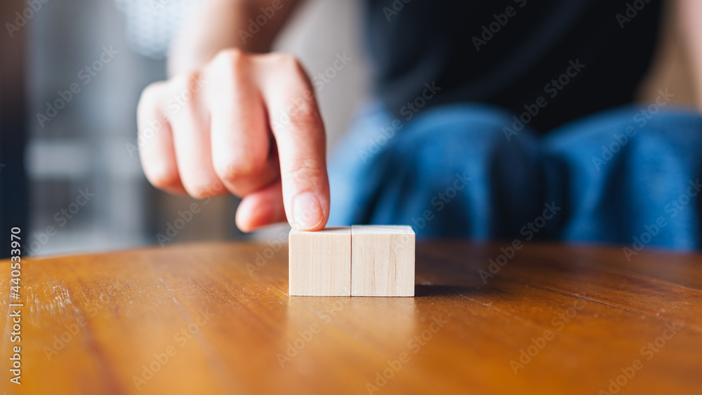 Closeup image of a hand choosing and picking two pieces of blank wooden cube block Closeup image of a hand choosing and picking two pieces of blank wooden cube block