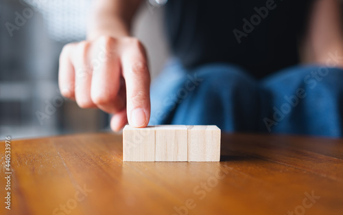 Closeup image of a hand choosing and picking three pieces of blank wooden cube block